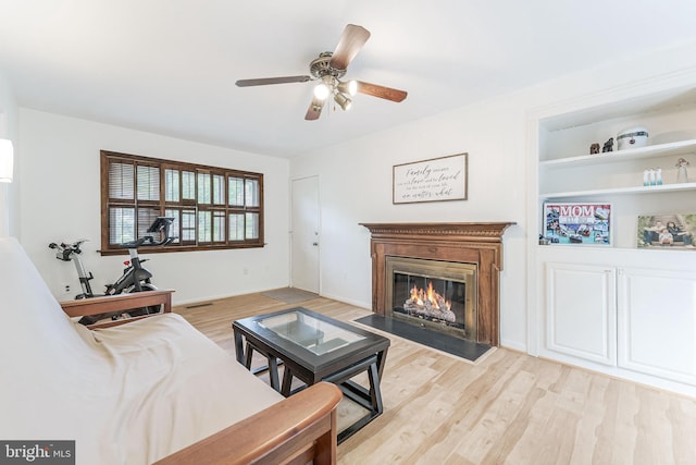 living room with a fireplace with flush hearth, light wood-style flooring, and ceiling fan