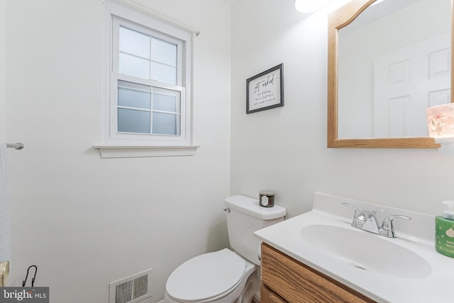 half bathroom with toilet, visible vents, and vanity