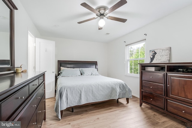 bedroom with light wood finished floors, a ceiling fan, and visible vents
