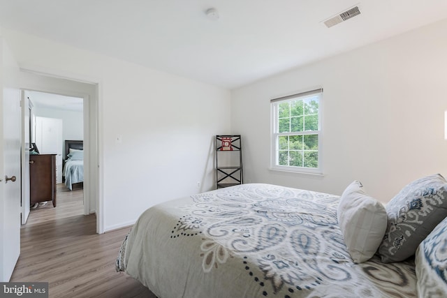 bedroom featuring light wood finished floors, visible vents, and baseboards