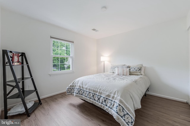 bedroom featuring baseboards, visible vents, and wood finished floors