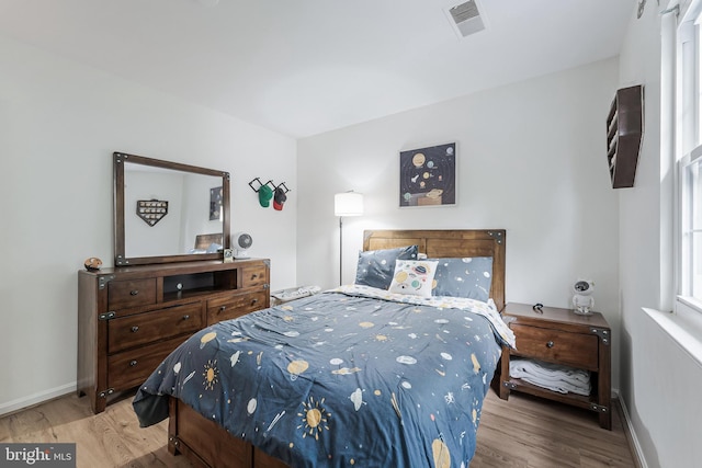 bedroom featuring baseboards, visible vents, and wood finished floors