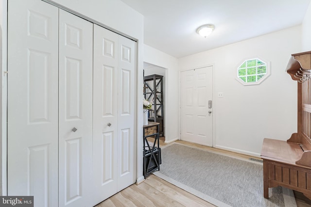 entryway with baseboards, light wood-style floors, and visible vents