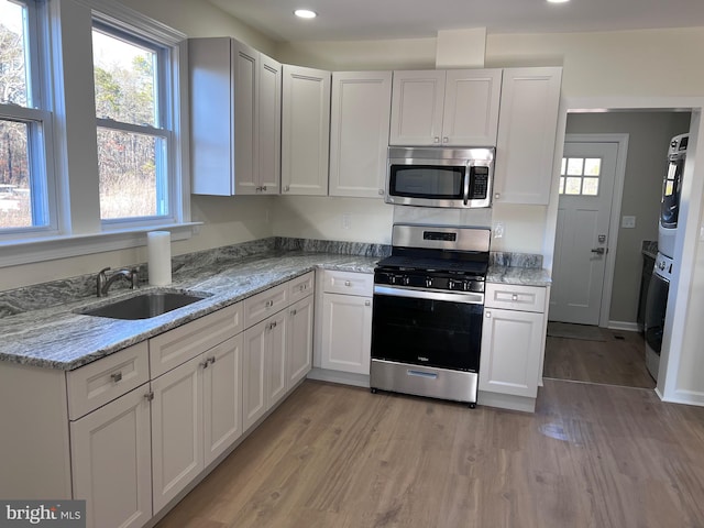 711 Tuckahoe Rd, Vineland, NJ 08360 - kitchen featuring a sink, appliances with stainless steel finishes, recessed lighting, stacked washer and clothes dryer, and light wood-style floors