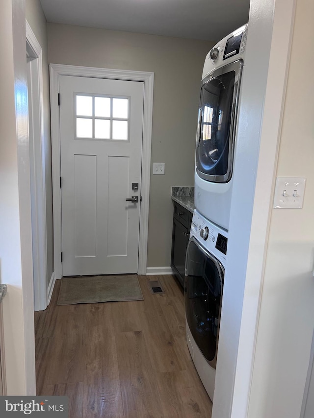 711 Tuckahoe Rd, Vineland, NJ 08360 - laundry area with baseboards, stacked washer and clothes dryer, cabinet space, and wood finished floors