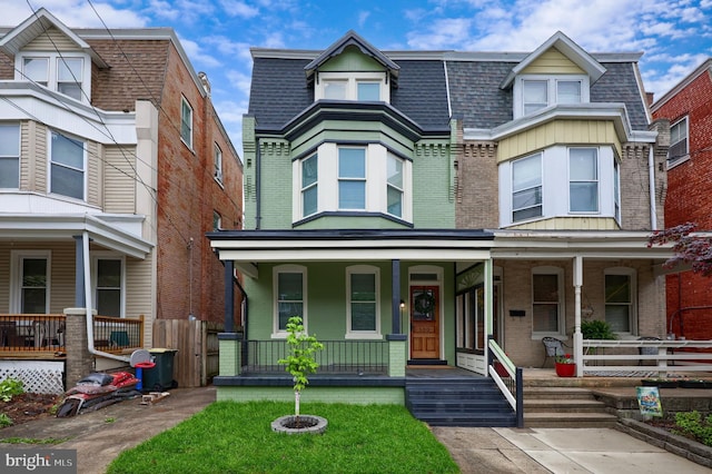 view of front of home featuring a shingled roof, brick siding, and covered porch