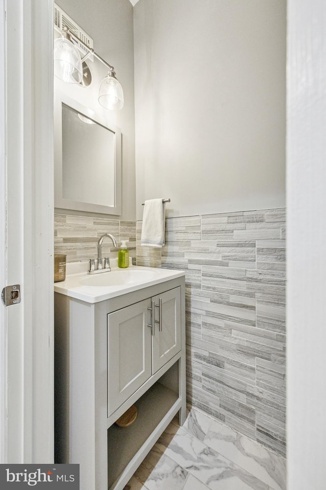 bathroom featuring vanity, tile walls, a wainscoted wall, and marble finish floor