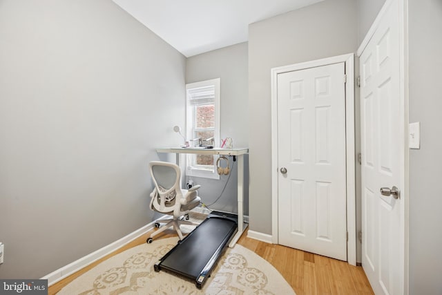 workout area with baseboards and wood finished floors