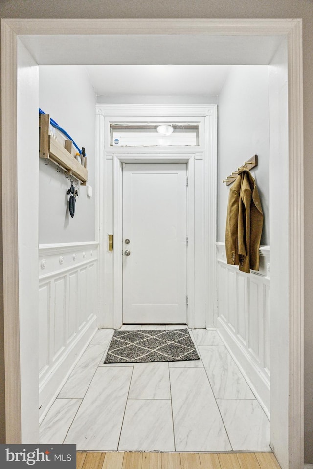 entryway with marble finish floor, a decorative wall, and a wainscoted wall