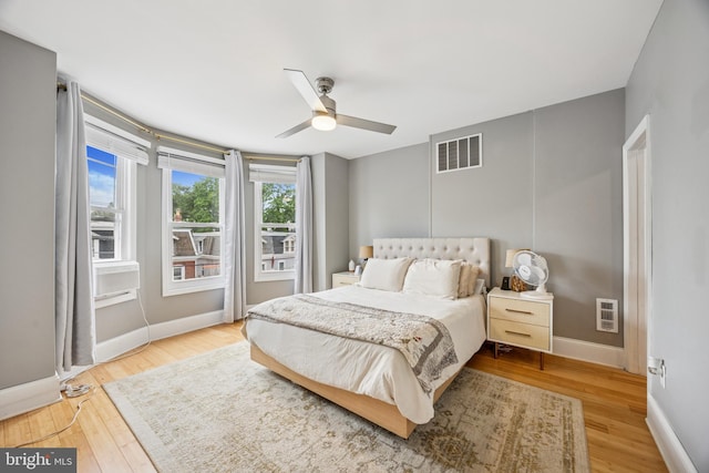 bedroom featuring heating unit, wood finished floors, a ceiling fan, visible vents, and baseboards