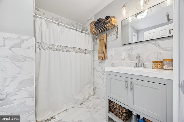 full bath with tile walls, marble finish floor, vanity, and a shower with curtain