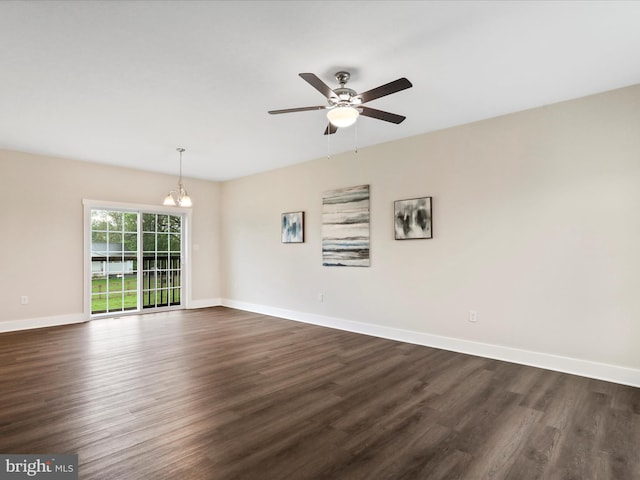 spare room with dark wood finished floors, a chandelier, baseboards, and a ceiling fan