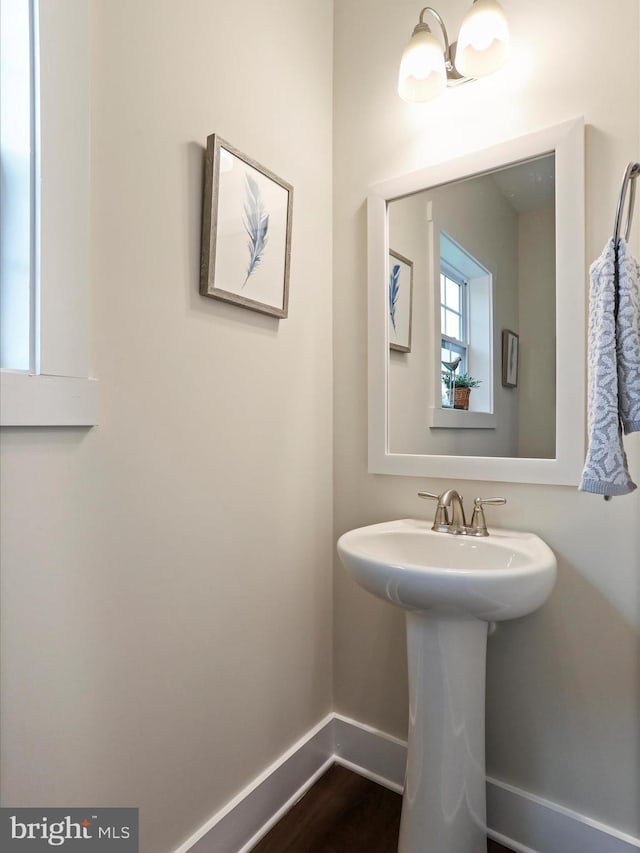 bathroom with baseboards, wood finished floors, and a sink