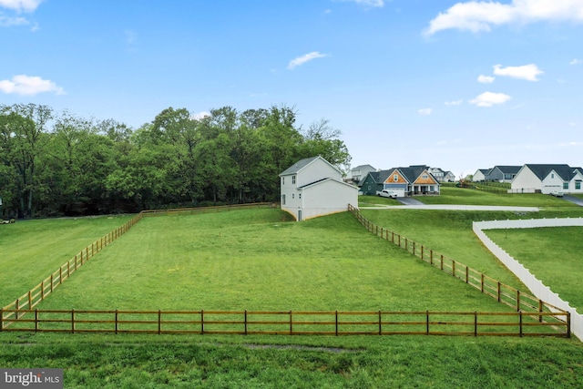 view of green lawn with a residential view, an outdoor structure, and a view of countryside