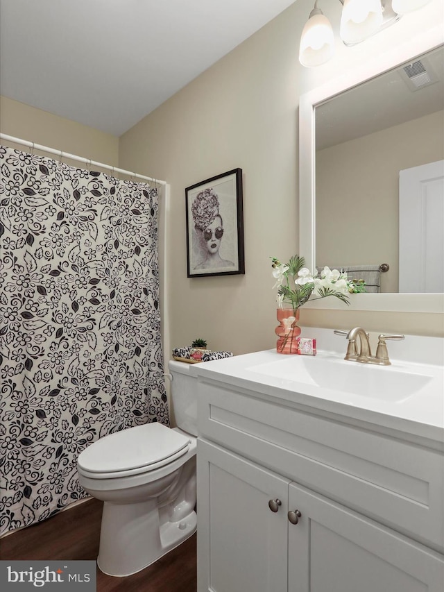 bathroom with toilet, vanity, and wood finished floors