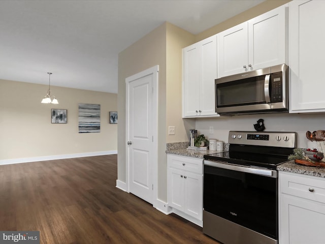 kitchen featuring stainless steel appliances, dark wood finished floors, white cabinetry, light stone counters, and hanging light fixtures
