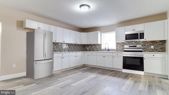 kitchen featuring light wood finished floors, white cabinets, appliances with stainless steel finishes, and decorative backsplash
