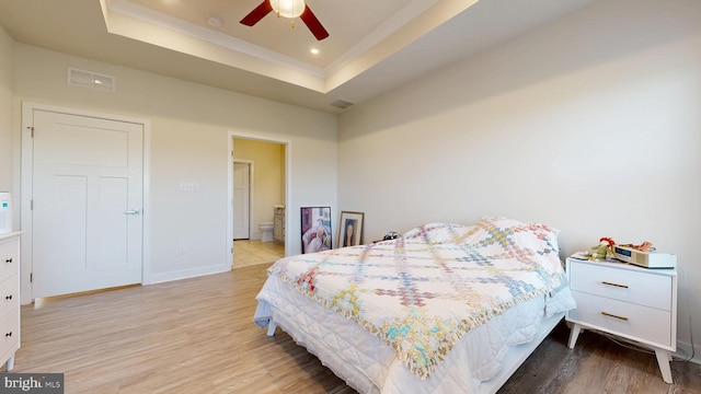 21042 Wavecrest Ter Unit 23, Lewes, DE 19958 - bedroom featuring a raised ceiling, wood finished floors, baseboards, ensuite bath, and crown molding