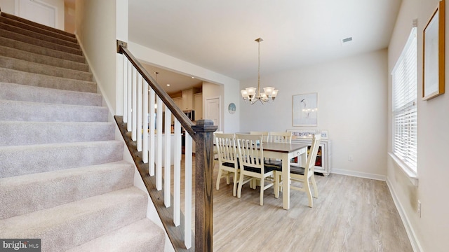 21042 Wavecrest Ter Unit 23, Lewes, DE 19958 - dining room with baseboards, stairway, an inviting chandelier, and light wood-style flooring