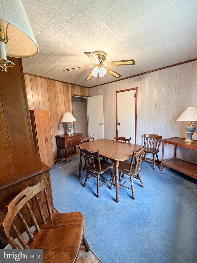 carpeted dining area with ceiling fan and an ornate ceiling