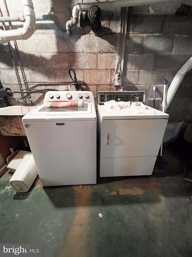 washroom with laundry area, concrete block wall, and washer and dryer