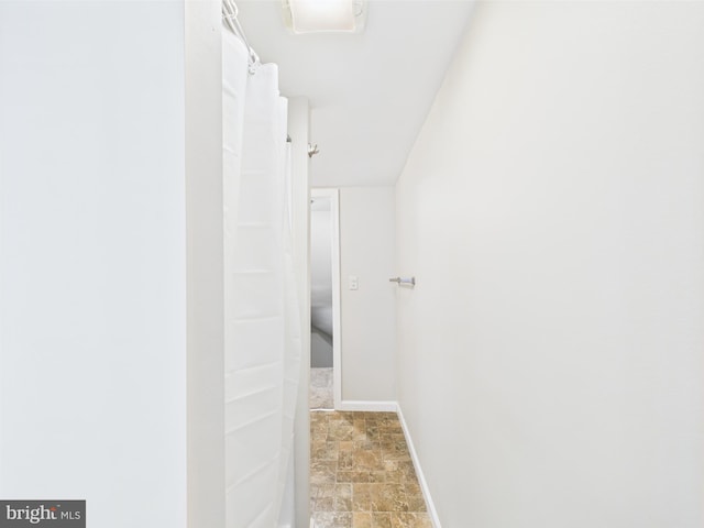 bathroom featuring walk in shower, baseboards, and stone finish flooring