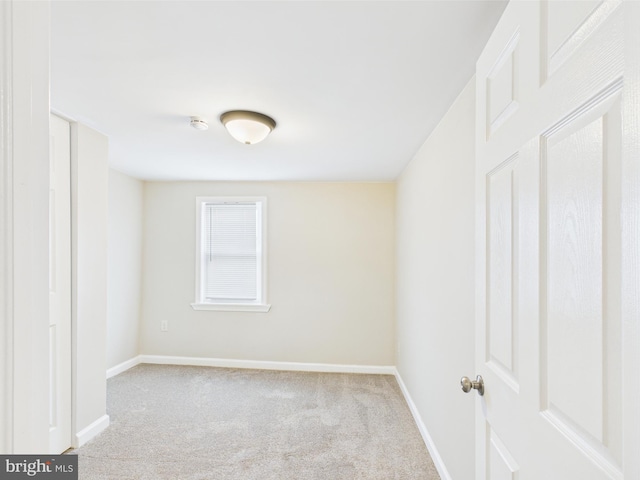 carpeted empty room featuring baseboards
