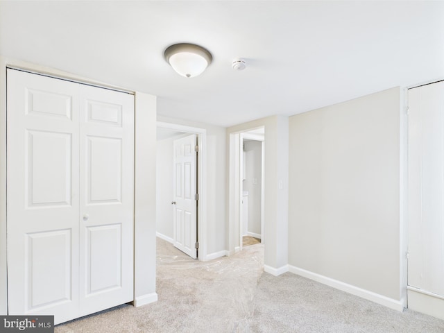 interior space featuring baseboards and light carpet