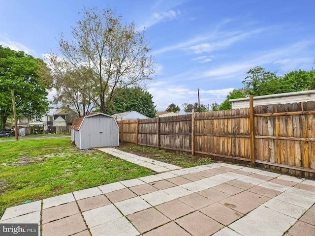 view of yard with a fenced backyard, a patio, a shed, and an outbuilding