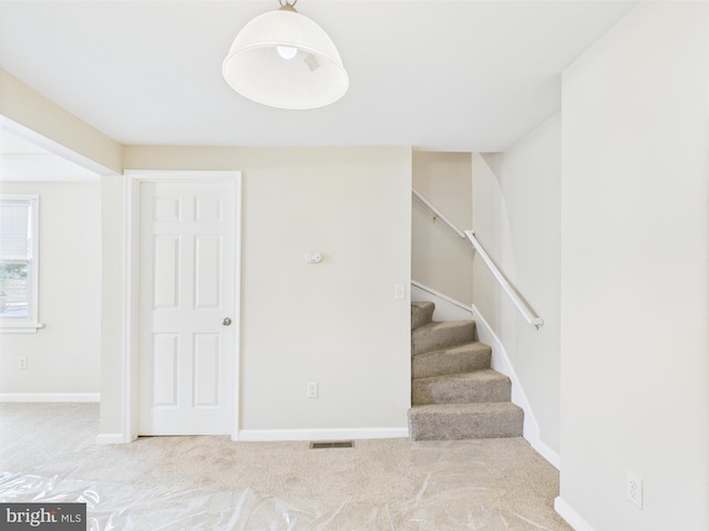 staircase featuring baseboards, visible vents, and carpet