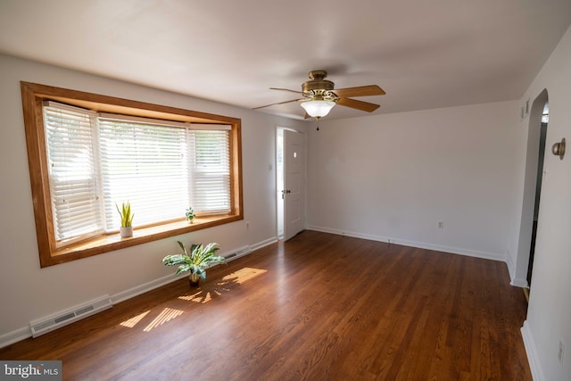 spare room featuring ceiling fan, wood finished floors, baseboards, and arched walkways