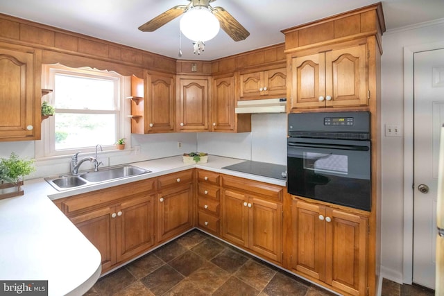 kitchen featuring black appliances, under cabinet range hood, a sink, crown molding, and light countertops