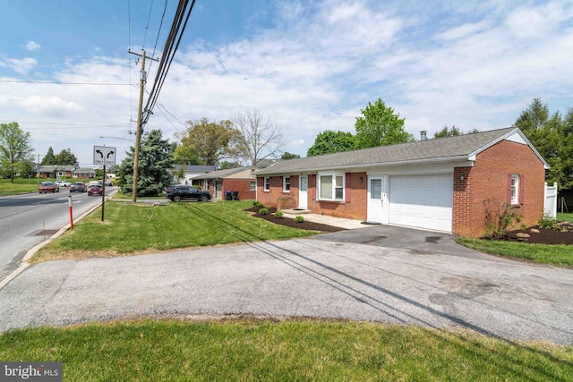ranch-style house with a garage, brick siding, driveway, and a front yard