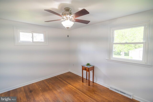 spare room with baseboards, wood finished floors, and ceiling fan