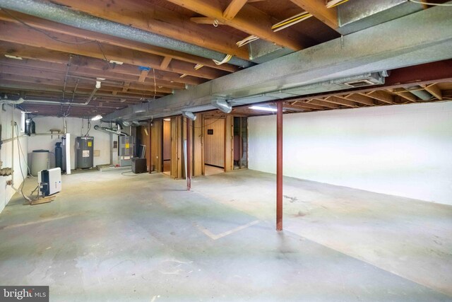unfinished basement with electric water heater and heating unit