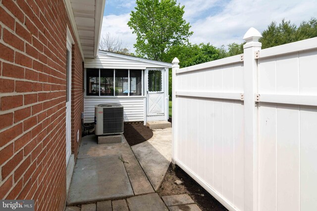 view of patio featuring cooling unit and a sunroom