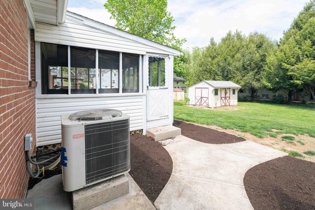 view of patio with cooling unit, a sunroom, a storage shed, and an outbuilding