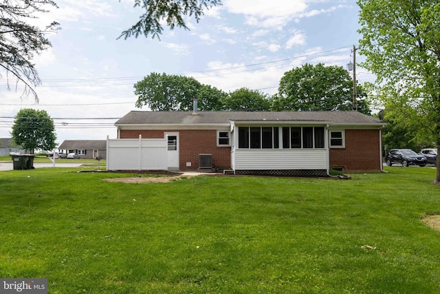 rear view of property with brick siding, central AC, and a lawn