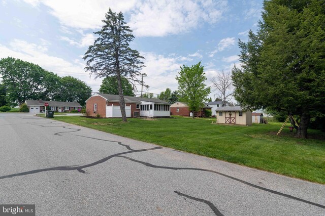 view of front of house with a front lawn, an outdoor structure, and a shed
