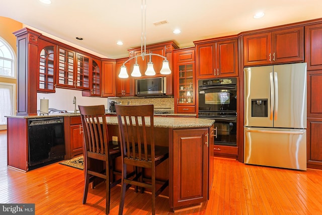 82 Granville Way, Exton, PA 19341 - kitchen featuring glass insert cabinets, decorative light fixtures, a kitchen island, black appliances, and light wood-style floors