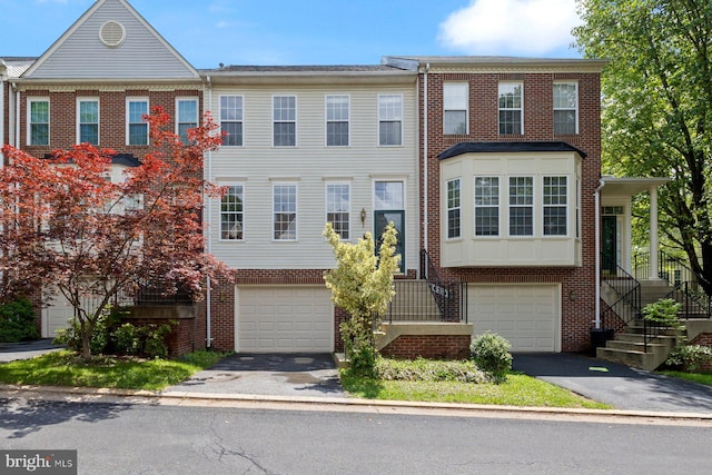 townhome / multi-family property with asphalt driveway, a garage, and brick siding