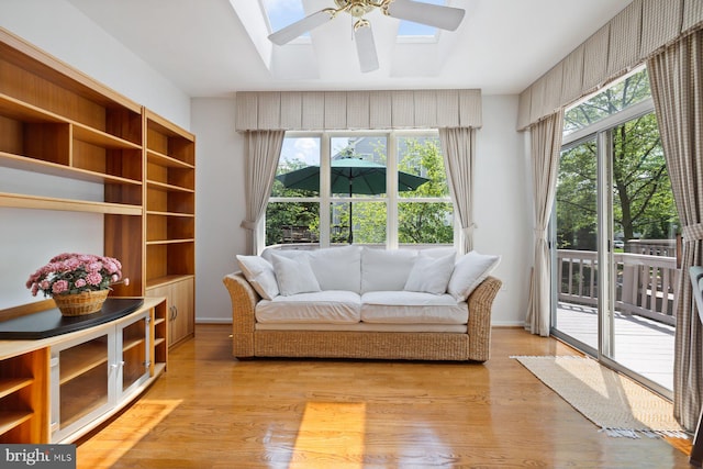 living area featuring a skylight, a ceiling fan, and light wood-style flooring
