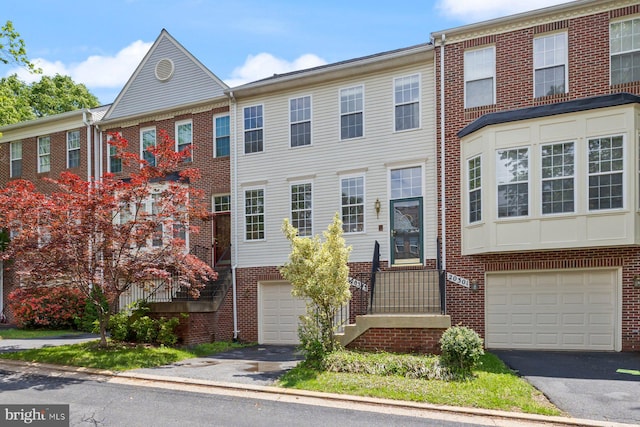 multi unit property with asphalt driveway, an attached garage, and brick siding