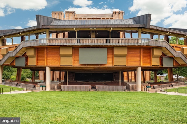 back of house featuring a standing seam roof, metal roof, a lawn, and a hot tub
