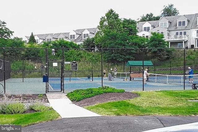 view of sport court featuring a gate, fence, and a residential view