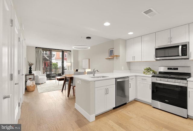 50 Florida Ave NE Unit 312, Washington, DC 20002 - kitchen featuring stainless steel appliances, a sink, a peninsula, light wood finished floors, and tasteful backsplash