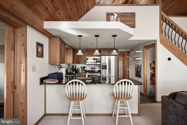 kitchen with stainless steel appliances, a peninsula, brown cabinetry, light colored carpet, and hanging light fixtures