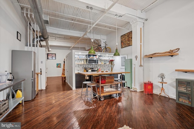 interior space with baseboards, a towering ceiling, and hardwood / wood-style flooring