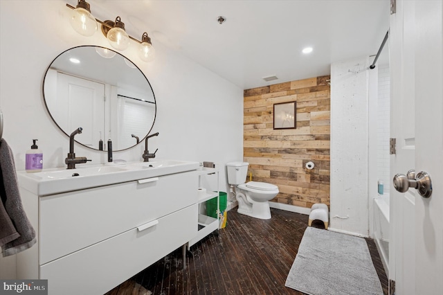full bathroom with toilet, wood walls, double vanity, hardwood / wood-style floors, and bathing tub / shower combination