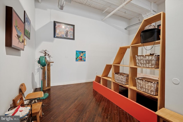 interior space with baseboards, beamed ceiling, and hardwood / wood-style floors